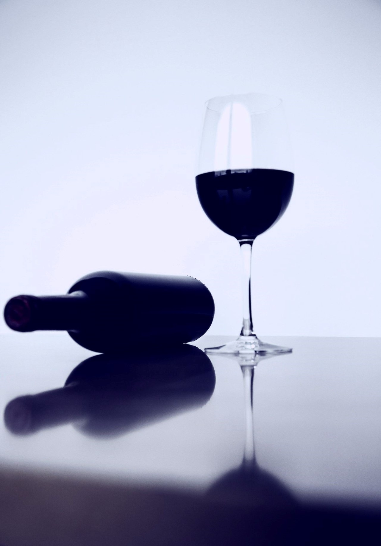 Glass of red wine, bottle tipped over